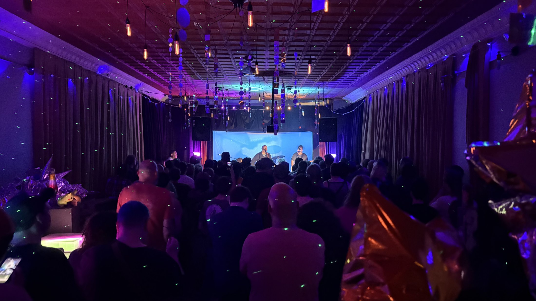 A full-color view of a live performance and audience at Glow Hall
